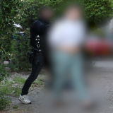 Tatverdächtiger ist unkenntlich gemacht und wird von Polizisten abgeführt.